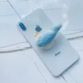 Détail d'un support de téléphone baleine en peluche bleue sur smartphone blanc - Support Extensible / Petit poisson bleu