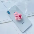 Detailed macro view of cute pink plush bear collapsible phone grip on a white smartphone - Expanding Stand / Pink Backpack Bear