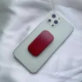 Supporto per telefono a spinta rosso attaccato al retro di uno smartphone grigio. - Supporto Scorrevole / Borgogna