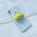 Détail d'un support de téléphone en peluche grenouille verte sur un smartphone blanc - Support Extensible / Grenouille aux Gros Yeux