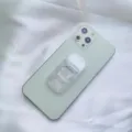 Primo piano di un supporto per telefono trasparente a molla su uno smartphone verde chiaro - Supporto Scorrevole / Trasparente