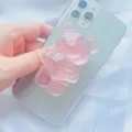 Close-up van een doorschijnende roze beer telefoonhouder bevestigd aan een smartphone - Uitbreidbare Standaard / Roze Translucent Beer