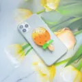 Detailopname van een oranje ijsje-vormige telefoonhouder op een witte smartphone. - Uitbreidbare Standaard / Ananas