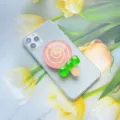 Detailopname van een roze lolly-telefoongreep van hars met een groene strik op de mobiel - Uitbreidbare Standaard / Lolly