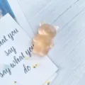 Close-up of a cute matte translucent bear-shaped phone grip on a decorative background. - Expanding Stand / Light Orange Frosted Bear