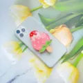 Detailopname van een schattige roze aardbeien-ijsje hars telefoonhouder op smartphone - Uitbreidbare Standaard / Melk Aardbei