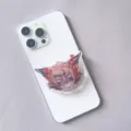Detail view of a cartoon anime character acrylic resin retractable phone grip on a white phone - Expandable Stand Style 2