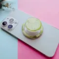 Vue détaillée d'un support de téléphone magnétique à motif floral vert sur un smartphone blanc. - Support Magnétique / Marguerite Verte