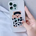 Nahaufnahme eines süßen Handy-Griffs aus Acryl in Bärenform an einem weißen Smartphone. - Erweiterbarer Ständer / Kuh Bär