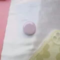 Gedetailleerde weergave van een macaron paarse ronde opvouwbare telefoonhouder op stof - Uitbreidbare Standaard / Lichtpaars