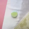 Close-up van een ronde macaron groene gradiënt telefoonhouder op witte zachte stof - Uitbreidbare Standaard / Verloop Groen