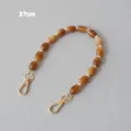 Détail d'une bandoulière en perles acryliques caramel de 37 cm avec fermoirs dorés. - 37cm / Couleur caramel