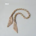 Gros plan d'une chaîne dorée élégante entrelacée d'un foulard en soie champagne. - Kaki (Or)