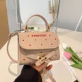Stylish beige square handbag with red polka dots and decorative gold belt buckle detail - Khaki