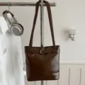 Borsa a secchiello minimalista in ecopelle marrone lucida con elegante dettaglio con fibbia. - senza ciondolo / Marrone