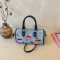 Stylish denim Boston handbag featuring embroidered cherries and a decorative charm - With Pendant / Blue