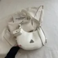 Elegant cream white crescent shoulder bag featuring wide grommet strap and mini coin pouch - Off White