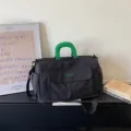 Black travel duffel bag with green handles and front pocket, lightweight large capacity. - Black