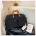 Zwarte reistas met oranje handvatten, grote casual sporttas en weekendtas voor korte trips. - Zwart