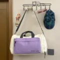 Large capacity travel duffel bag with shoulder strap and purple front pocket, hanging view. - White and Purple