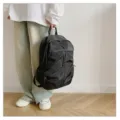 Detalle de una persona sosteniendo una gran mochila negra casual sobre un fondo de pared blanca - Negro