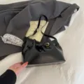 Elegante zwarte leren emmertas met gouden riemgesp in een modieuze lifestyle-setting - Zwart