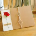 Biglietto di auguri retrò in carta kraft con un piccolo fiore secco rosso e spago rustico - Rosa (Fiore Artificiale)