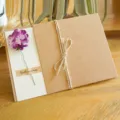 Biglietto d'auguri vintage in carta kraft con fiore secco viola e etichetta Best Wishes - Garofano Viola (Fiore Artificiale)
