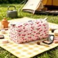 Close-up of pink velvet makeup bag with cherry and bow pattern in outdoor picnic scene - L / Pink Cherry