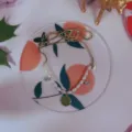 Nahaufnahme Detail einer zarten Perlenkette mit Kristallanhängern auf einem Pfirsichtablett. - Orangen-Matten