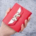 Stylish red women's short wallet with white flap and decorative golden bow detail - Red