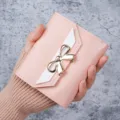 Elegant pink women's short wallet with a stylish gold bow decoration and white accent - Pink