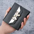 Black women's short wallet with elegant gold bow decoration and white flap detail - Black