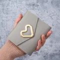 Elegant grey faux leather coin purse with a modern geometric gold heart-shaped buckle - Gray
