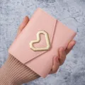 Elegant pink faux leather card holder featuring a stylish gold geometric heart ornament. - Pink