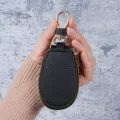 Compact zwart lederen autosleuteletui met elegante goudkleurige rits en haakje. - Zwart