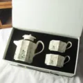 Set da tè in ceramica teiera e tazze in confezione regalo con elegante design floreale. - Set Regalo Teiera e Due Tazze Iris / Beige