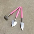 Close-up detail of mini gardening tools set, small shovel and rake with pink handles for plants. - Three-Piece Set / Pink
