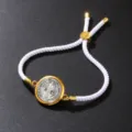 Close-up detail of a vintage white cotton rope bracelet with an adjustable golden coin pendant - Bracelet / White