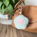 Close-up of a mink fur flower bag charm with a pink center on a brown leather bag. - Heart Version Hardware - Pea Green & Pink