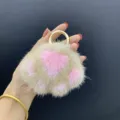 Detailopname van een zachte nertsbont kattenpoot sleutelhanger met een glanzende gouden ring - Kakikleur en Roze