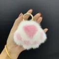 Macro-detail van een zachte wit-roze nertsbont kattenpoot sleutelhanger in een hand - Roze Paars + Wit