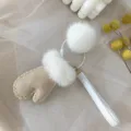 Close-up of a cute mink fur mitten keychain with white pom-pom for bag charm accessory - White