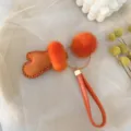 Detail view of a cute orange fur glove keychain charm with fluffy mink fur pom-poms for bags. - Orange