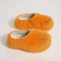 Detailed view of orange fuzzy monster paw slippers with silver claws and thick soles. - Orange