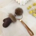 Close-up of cute brown mitten keychain featuring real mink fur pom pom and leather strap - Brown