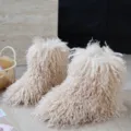 Gros plan détaillé sur la fausse fourrure bouclée crème des bottes de neige pour enfant - Abricot