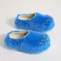 Macro view of blue faux fur mule slippers featuring decorative silver metallic claws - Blue