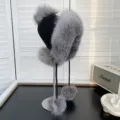 Primer plano de un gorro de punto negro con lujoso ribete y pompones de piel de zorro gris. - Talla única / Color Natural de Piel de Zorro Plateado