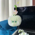 Gedetailleerde close-up van een schattige groene en witte pluche kattenhanger aan een laptop - Groen
